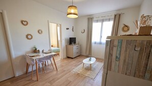Ein modernes Wohnzimmer mit Essbereich, Holzboden, einem runden Couchtisch und einer Pendelleuchte.