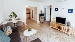 A modern living room with a sofa, coffee table, TV, and a dining area with chairs and a table. - Apt. Urbanization Las Lanzas, Muchavista beach (Fabraquer)