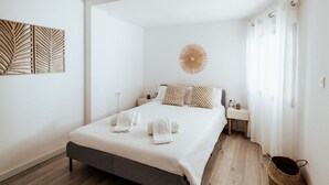 A clean, modern bedroom with a bed, bedside tables, a wall art piece, and a ceiling fan. - Apt. Urbanization Las Lanzas, Muchavista beach (Fabraquer)