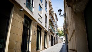A narrow urban street with buildings on both sides, featuring large windows and a street lamp. - Apto. Abad Najera, en el Centro de Alicante (Alicante (Alacant))