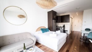 A modern hotel room with a bed, a sofa, a dining area, and a kitchen in the background. - Apto. Abad Najera, en el Centro de Alicante (Alicante (Alacant))