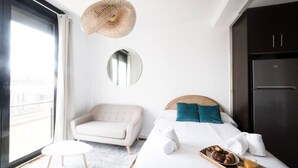 A hotel room with a bed, a sofa, a round mirror, a hanging light fixture, and a refrigerator. - Apto. Abad Najera, en el Centro de Alicante (Alicante (Alacant))
