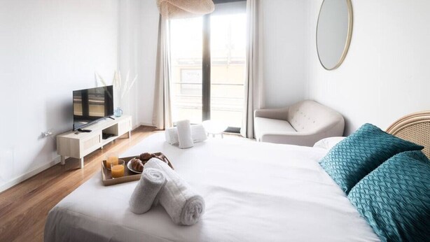 A modern hotel room with a bed, a TV, a chair, and a window with curtains. - Apto. Abad Najera, en el Centro de Alicante (Alicante (Alacant))