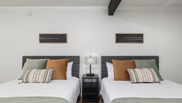 A twin room with two beds, a nightstand with a lamp, and two wall-mounted signs.
