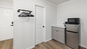 A compact kitchen with white cabinetry, a stainless steel refrigerator, and a microwave. - The Lofts on Indian Point (Branson)