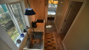 Une cuisine de taille réduite, dotée d’une fenêtre, d’un évier et d’une machine à café.