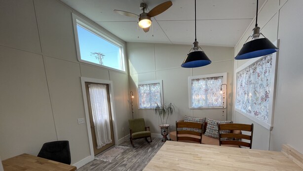 Une cuisine moderne avec un îlot central en bois, des luminaires suspendus et un ventilateur de plafond.