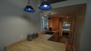 Une cuisine avec des plans de travail en bois, deux suspensions lumineuses, une fenêtre et un évier.