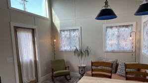 Un coin repas comprenant une table en bois, deux chaises, un fauteuil vert et un vase à motifs.