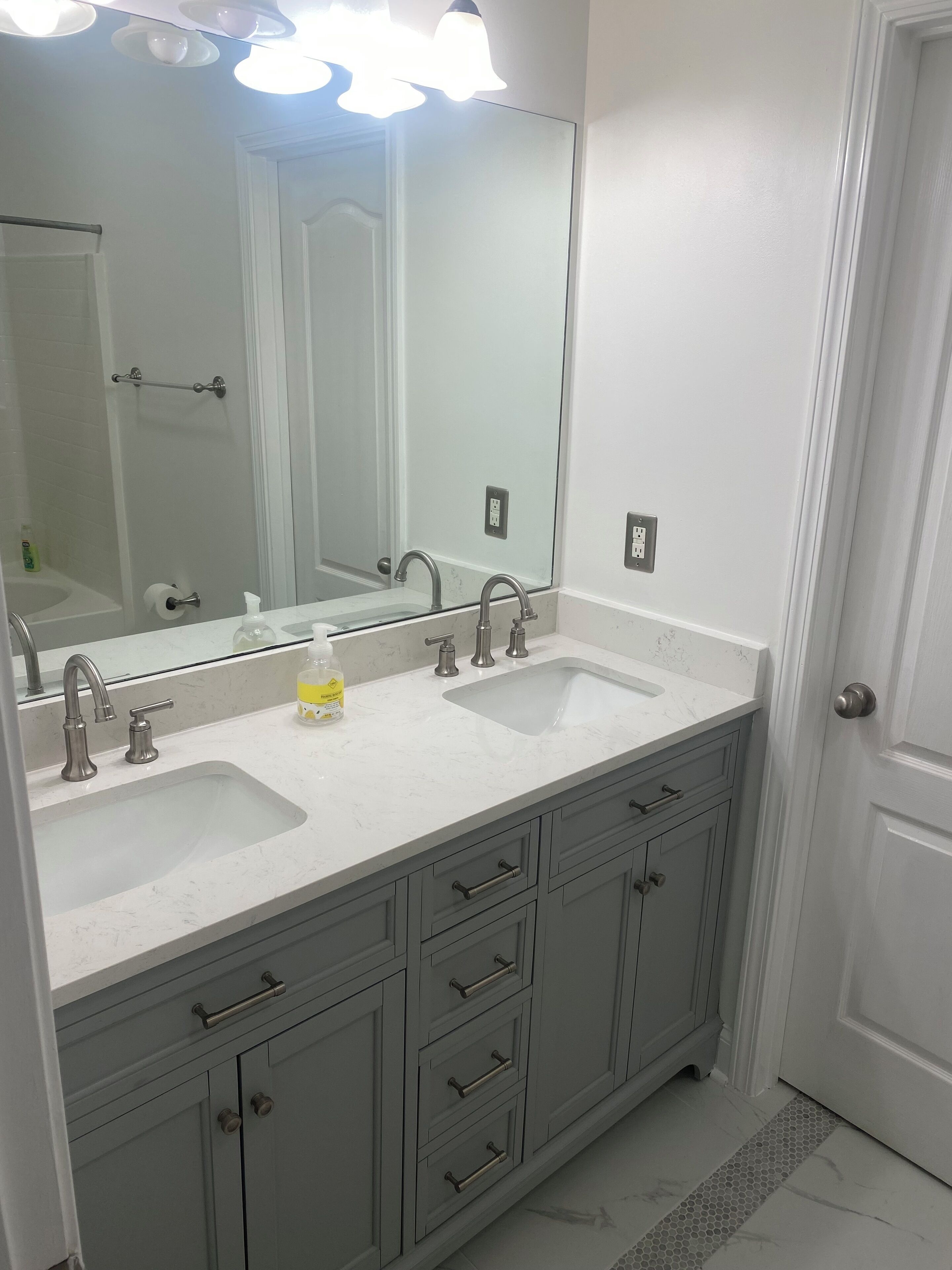 A bathroom with two sinks, a large mirror, and a shower.