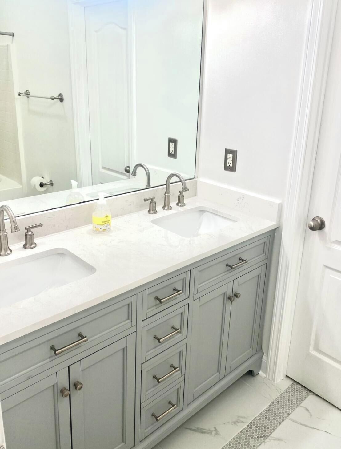 Une salle de bain avec un double lavabo, un grand miroir et un meuble avec des tiroirs.