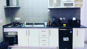 A compact kitchen with a gas stove, a sink, a dishwasher, and a microwave. - Charming 1-bed Apartment in Victoria Island, Lagos (Lagos)