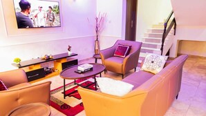 A modern living room with a sofa, armchairs, a coffee table, and a TV mounted on the wall. - Captivating 3-bed Apartment in Lagos (Lekki)