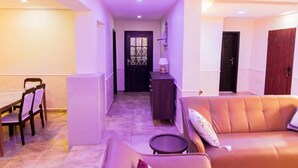 A hallway with a dining area on the left, a sofa on the right, and a door at the end. - Captivating 3-bed Apartment in Lagos (Lekki)