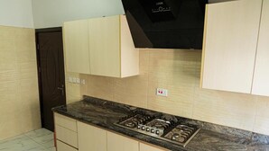 Une cuisine avec des armoires de couleur beige, une hotte noire et une cuisinière à gaz.