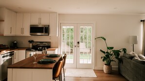 Una cocina moderna con armarios blancos, una isla de madera y un comedor.