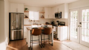 Una cocina moderna con armarios blancos, electrodomésticos de acero inoxidable y una zona de bar con taburetes.