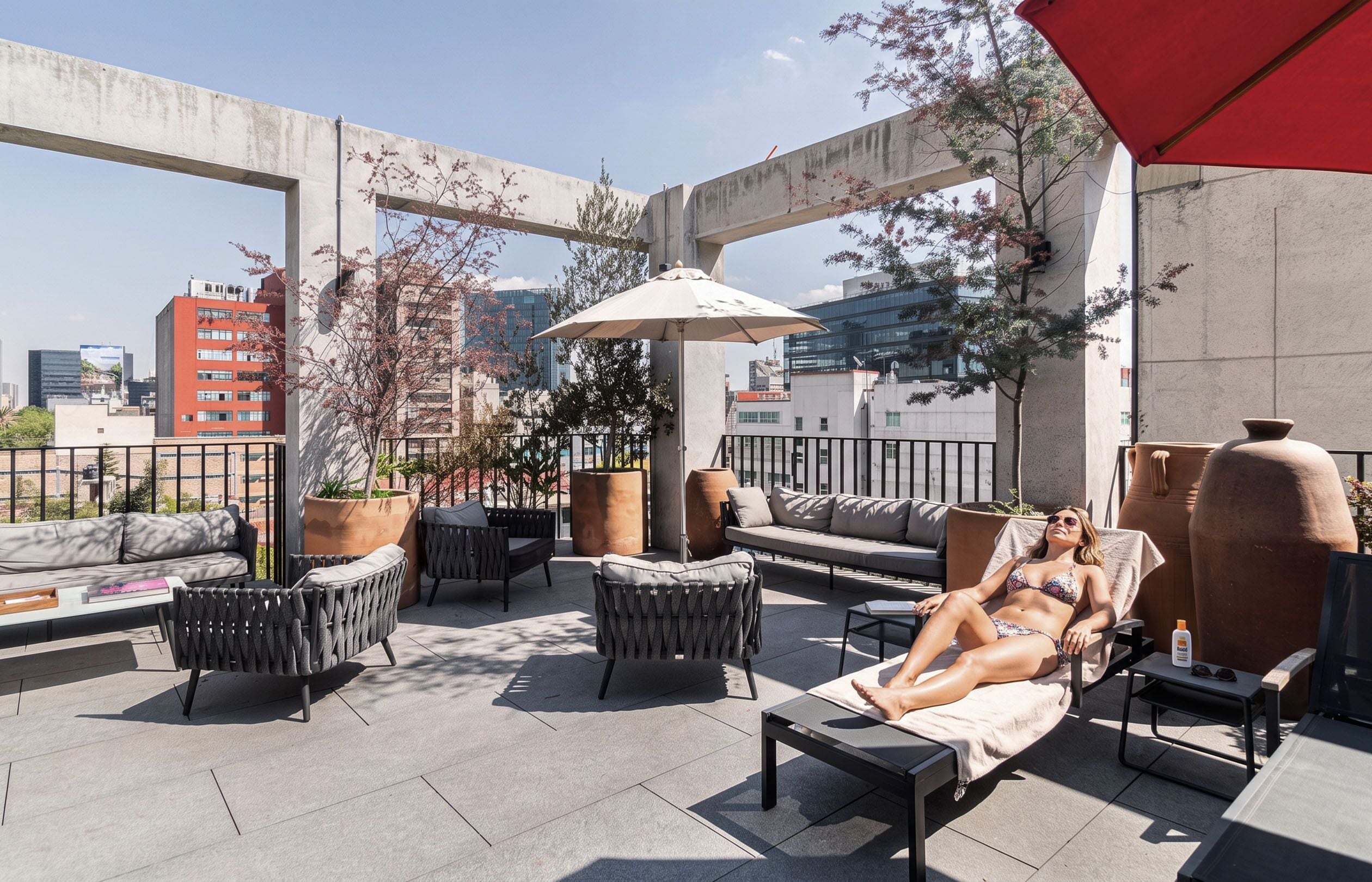 A rooftop terrace with outdoor furniture, a large umbrella, and potted plants.
