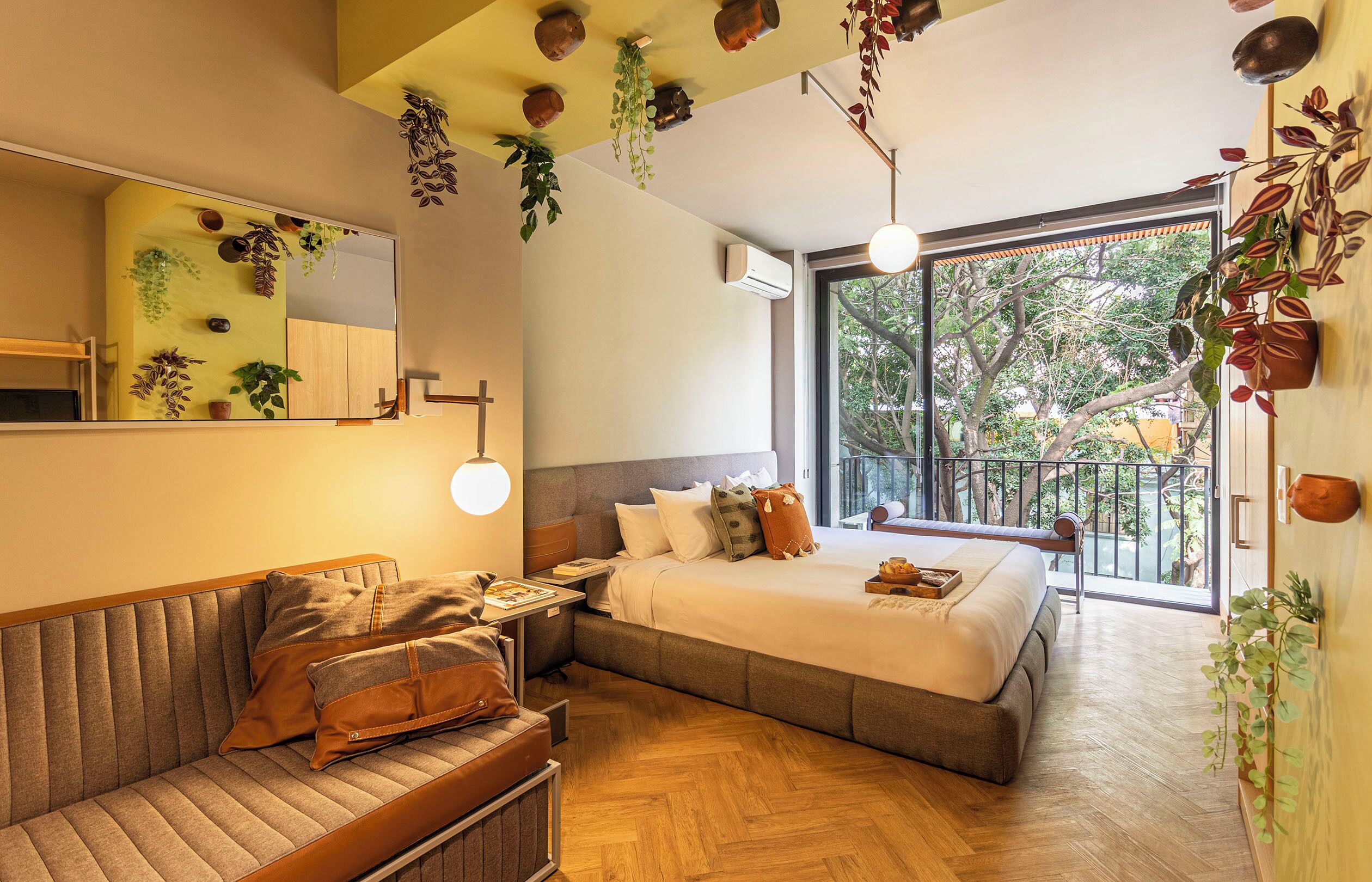 Ein modernes Schlafzimmer mit einem großen Bett, einer Couch und einem Balkon mit Pflanzen.