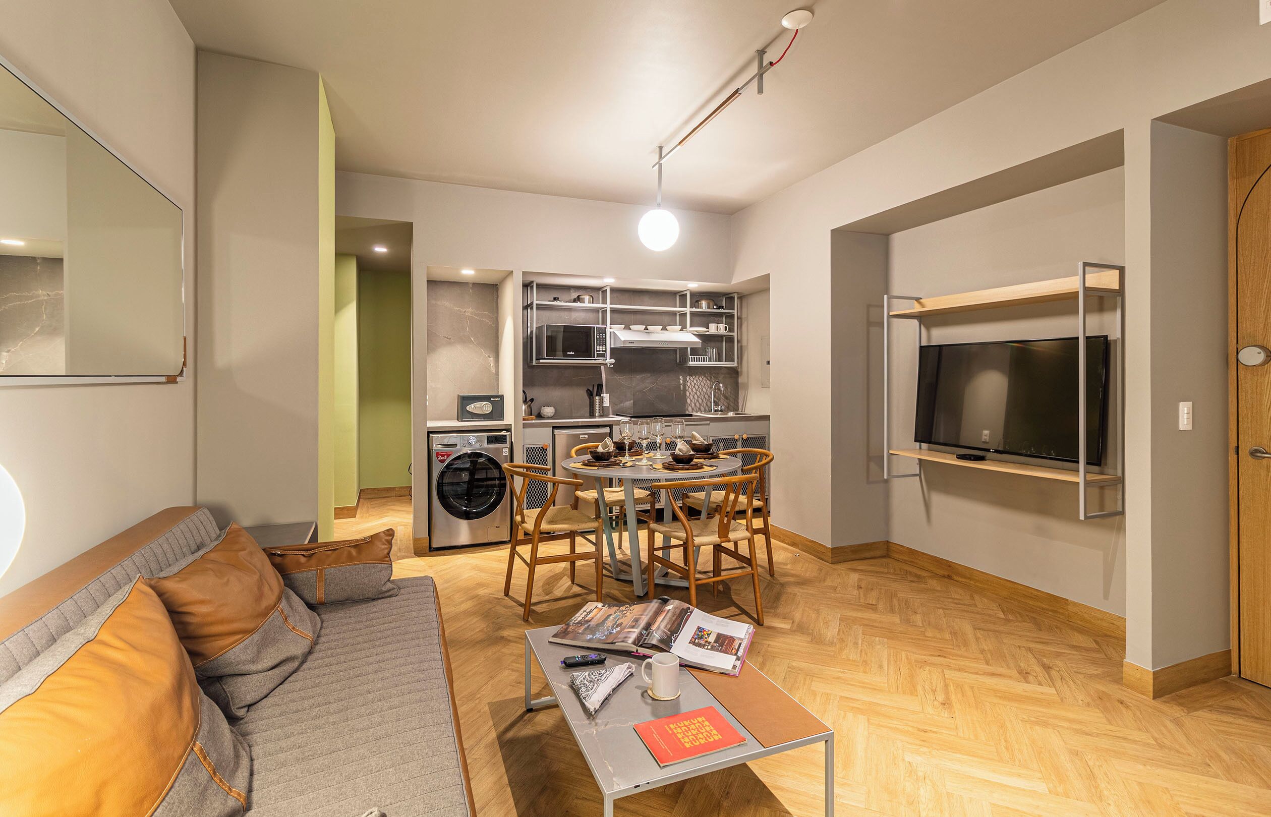 A compact living space with a kitchenette, a dining area, and a seating area with a sofa and coffee table.