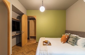 Ein Schlafzimmer mit einem Bett, einem Holzschrank, einem Fernseher und einer Lampe.