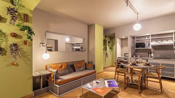 Un espace de vie compact comprenant un canapé, une table à manger et un coin cuisine.