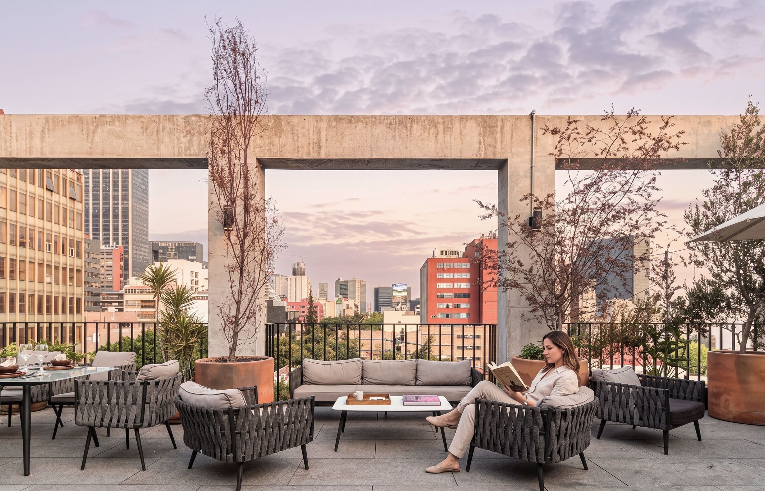 Eine Dachterrasse mit Sitzgelegenheiten im Freien, Blick auf die Stadt und einer darüberliegenden Betonkonstruktion.