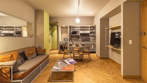 A compact living space with a sofa, coffee table, dining table, and kitchen area.