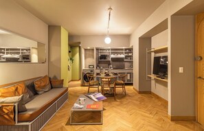 A compact living space with a sofa, coffee table, dining table, and kitchen area.