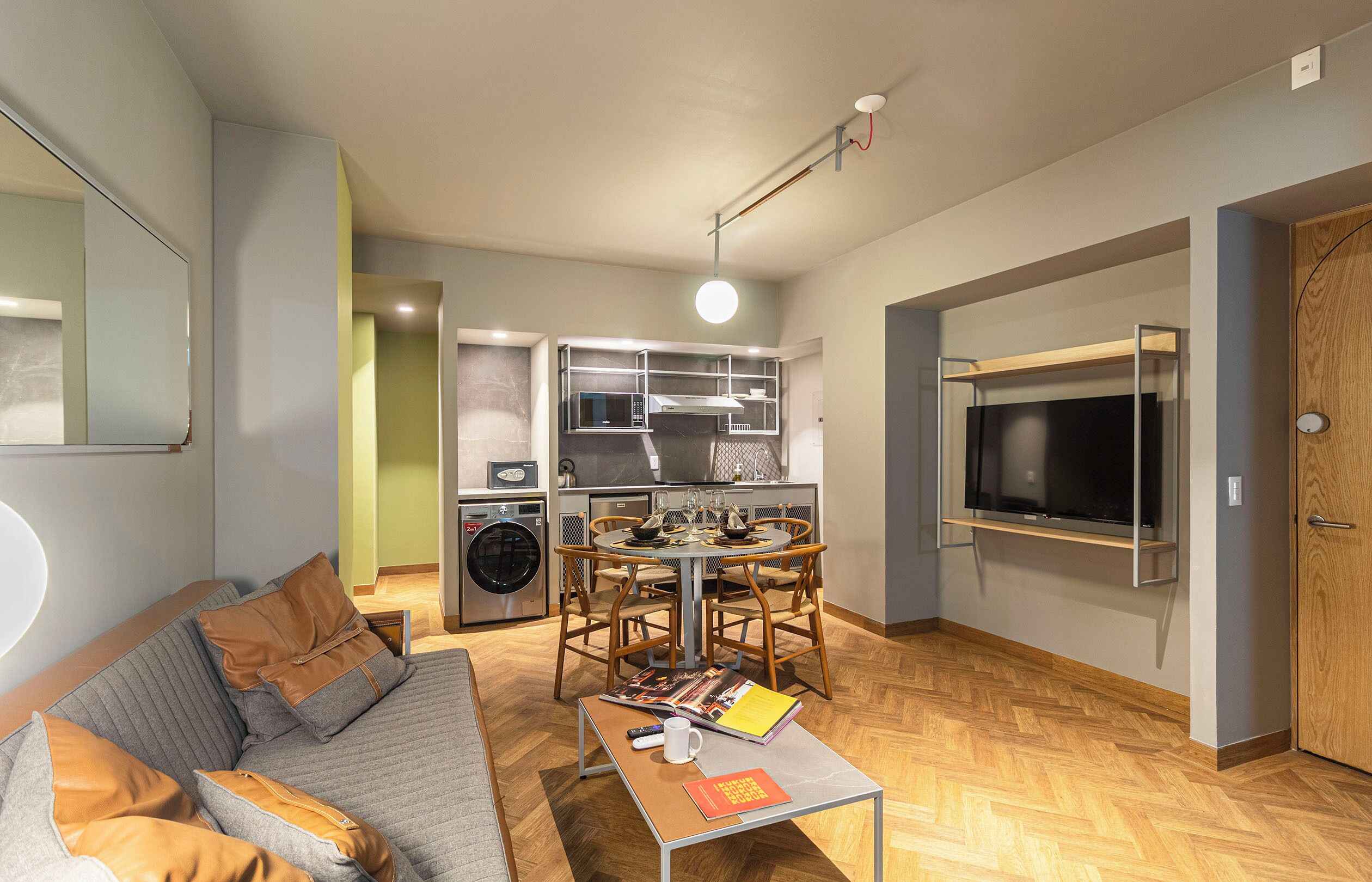 A compact living space with a sofa, dining table, and a television mounted on the wall.