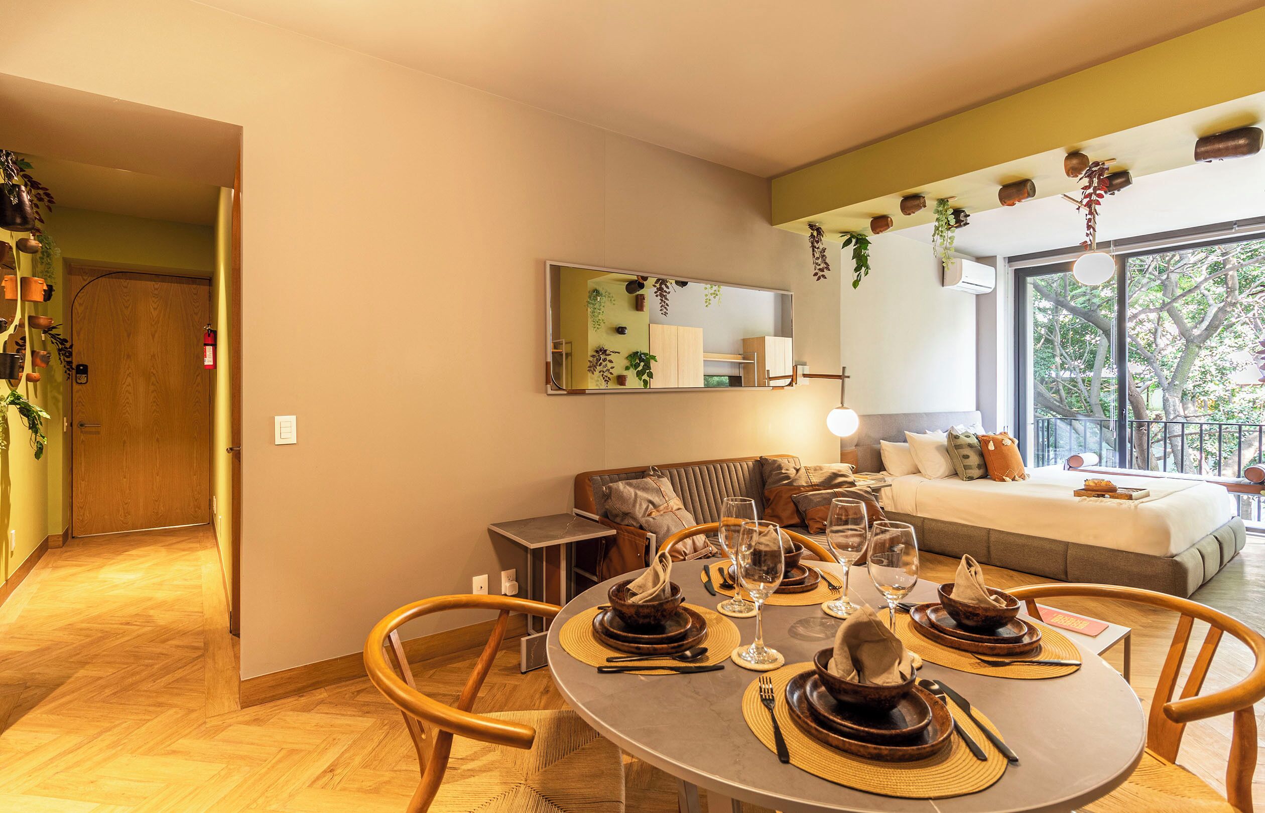 Un coin repas avec une table ronde dressée pour quatre personnes, un canapé et un lit en arrière-plan.
