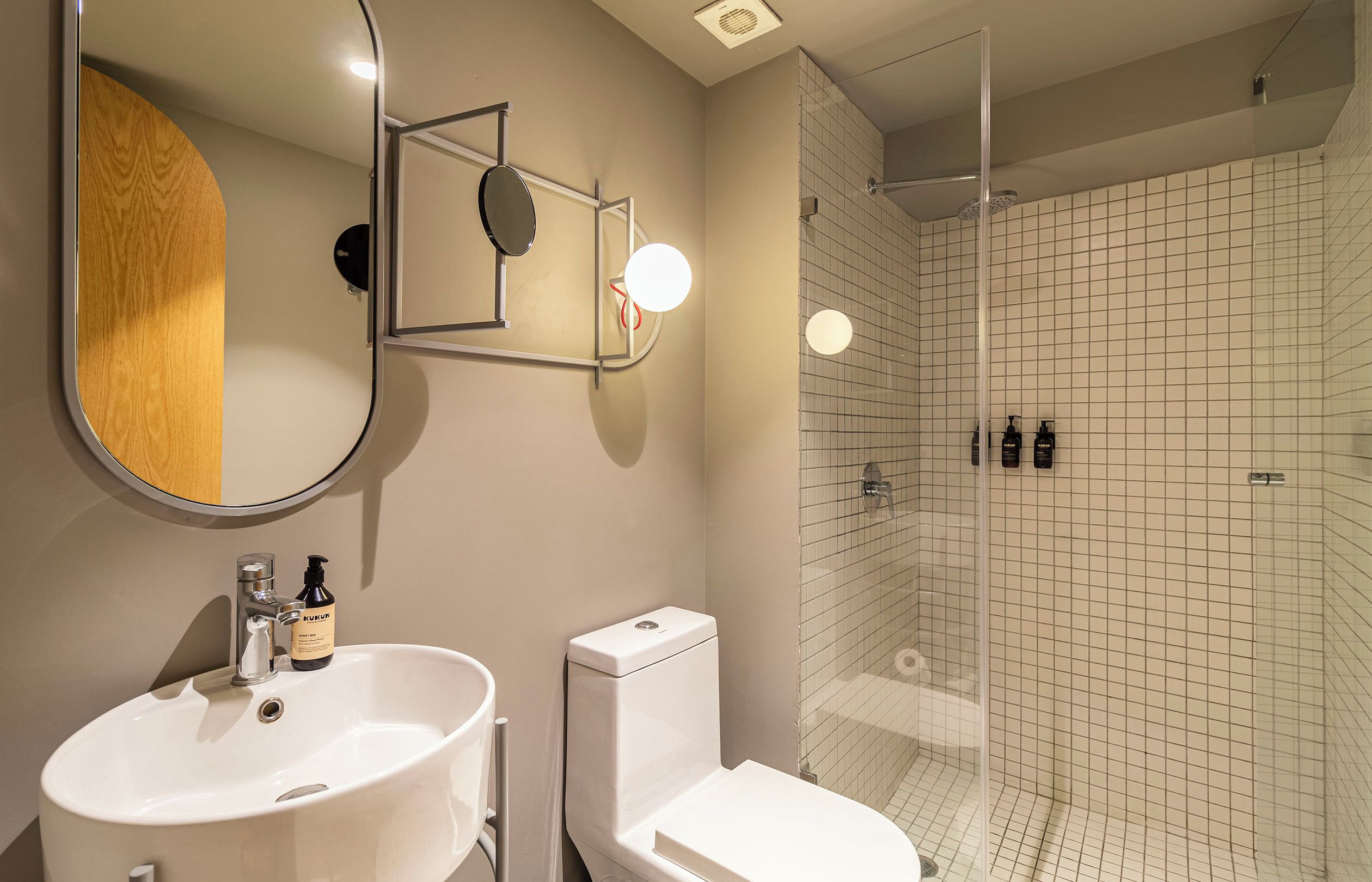 A bathroom with a white sink, toilet, and a glass-enclosed shower with tiled walls.