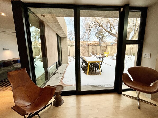 A modern interior with a sliding glass door leading to a patio area with a table and chairs. - Casa Solana Retreat - 5 minutes to the Plaza, nearby shopping (Santa Fe)