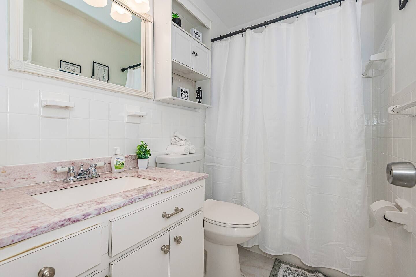 A bathroom with a marble sink, a toilet, a shower curtain, and a mirror.