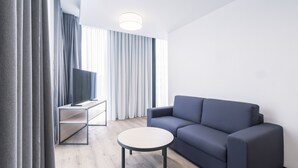 Un salon moderne avec un canapé, une table basse ronde et un téléviseur posé sur un meuble.