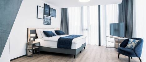 Una habitación de hotel moderna con una cama, un escritorio, una silla y un televisor.