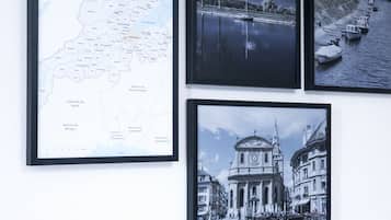A wall with four framed pictures: a map, a night scene, a river scene, and a historical building.