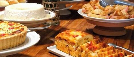 Een buffettafel met diverse gerechten, waaronder taart, quiches en voorgerechten.