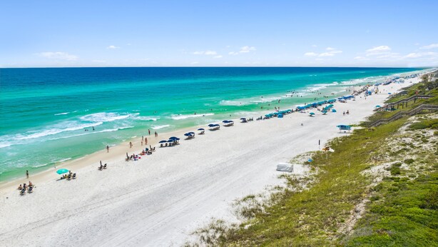 A beach with a long stretch of white sand, clear turquoise water, and a few umbrellas and beach chairs. - Beachwood Villas by Panhandle Getaways (Santa Rosa Beach)