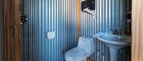 Un baño pequeño con inodoro, lavamanos y secador de manos.