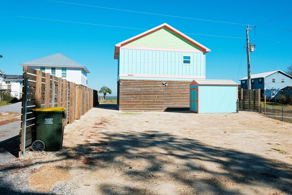 A two-story building with a garage, a wooden fence, and a green trash bin.
