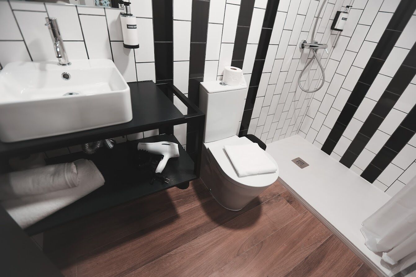 A modern bathroom with a white sink, black countertop, and a toilet.