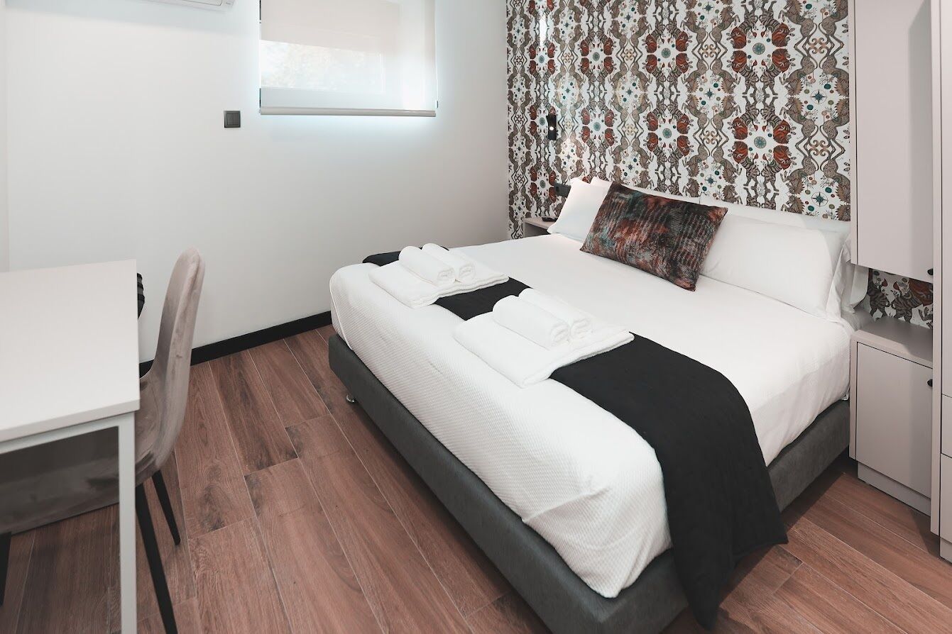 A modern bedroom with a bed, a desk, and a chair.