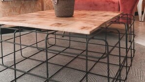 Um quarto aconchegante com uma poltrona vermelha, uma mesa de centro de madeira e um vaso com planta.