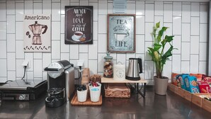 Uma cozinha com máquina de café, chaleira, uma planta e diversos alimentos no balcão.