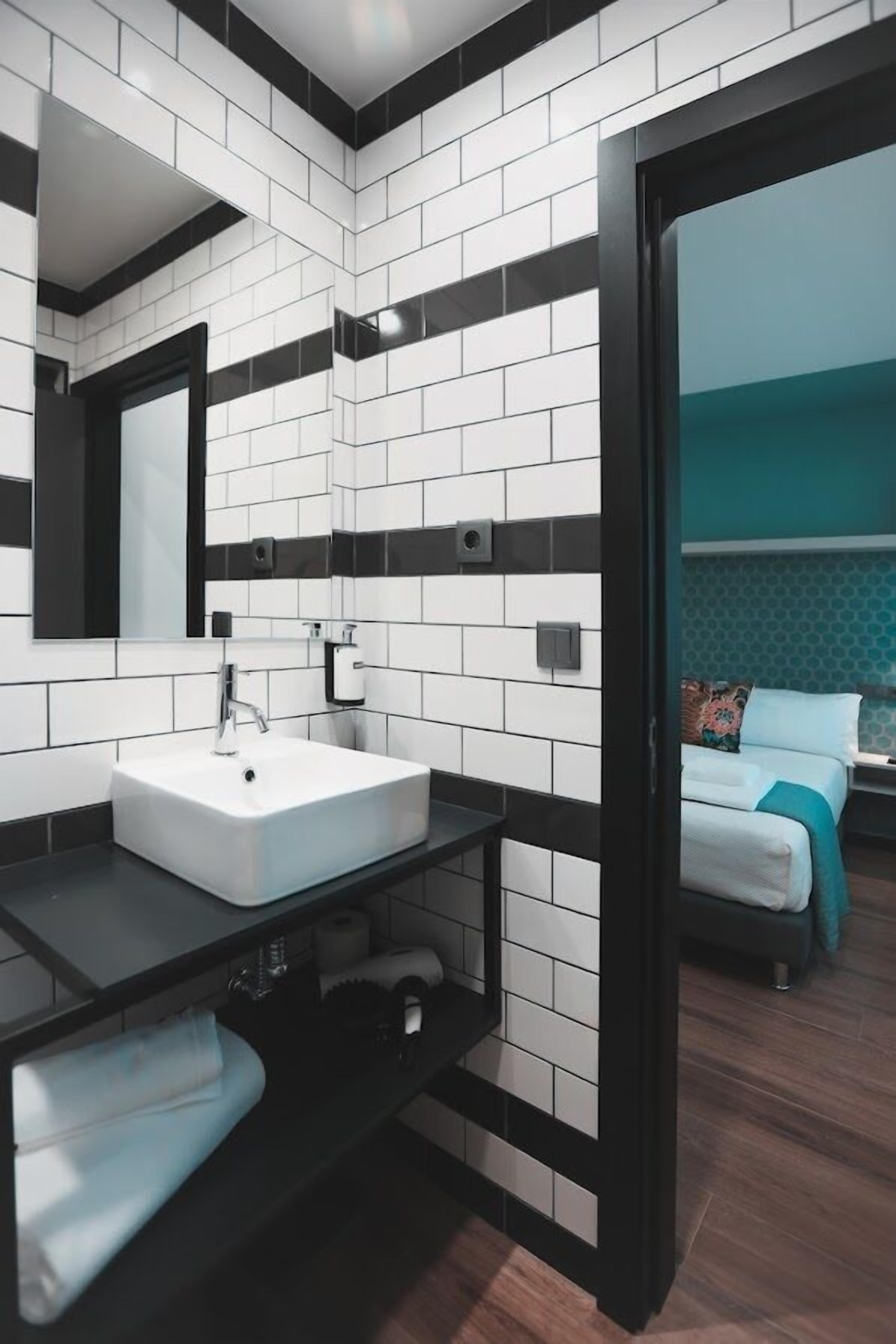 A modern bathroom with a white sink, black countertop, and a mirror.