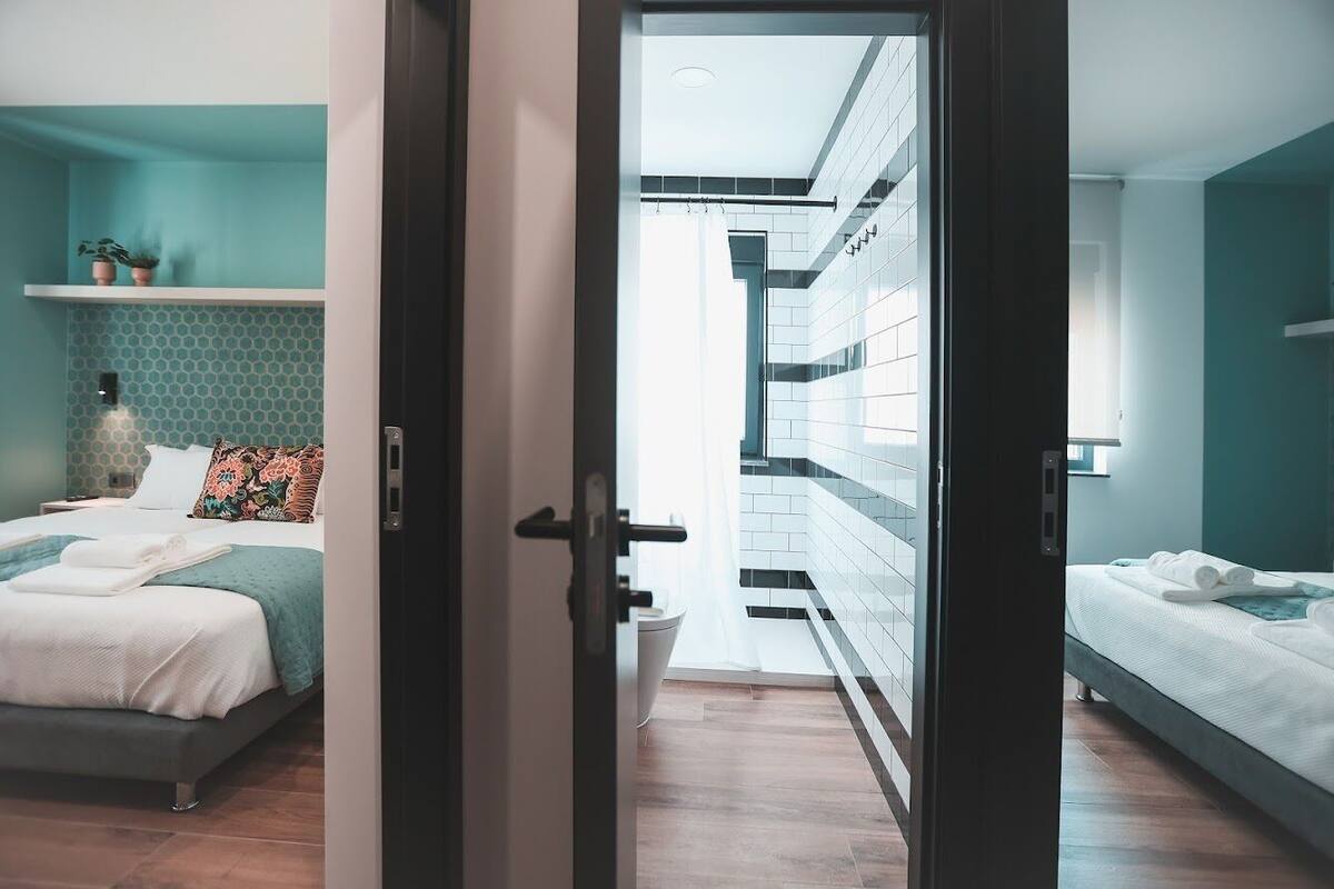 A modern bedroom with a bed, a nightstand, and a wall-mounted shelf with plants.