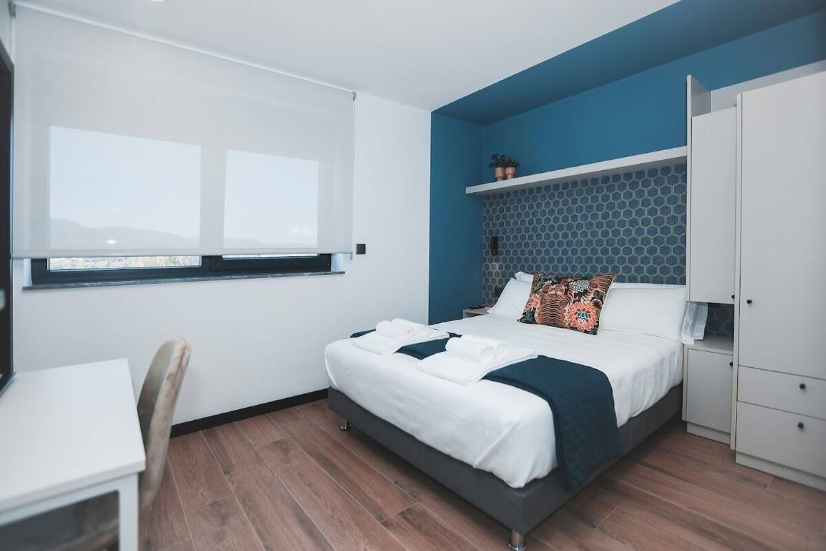 A modern bedroom with a bed, bedside table, and a window.