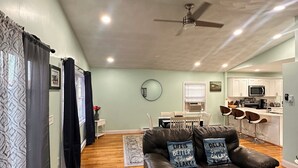 A spacious living area with a leather sofa, a dining table, and a kitchen in the background.