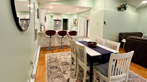 A dining area with a table and chairs, a patterned rug, and a ceiling with recessed lighting.